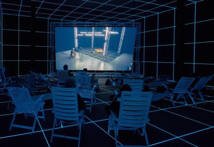 Hito Steyerl, Factory of the Sun, 2015, një kanal high definition video, mjedisi, luminescent LE grid, karriget e plazhit, 23 minuta. Pamja